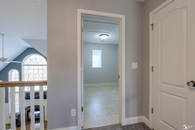 hallway featuring vaulted ceiling and light tile patterned floors