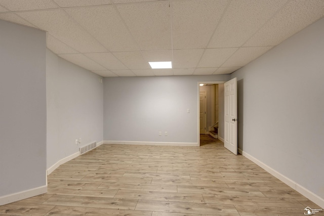 empty room featuring a drop ceiling and light wood-type flooring