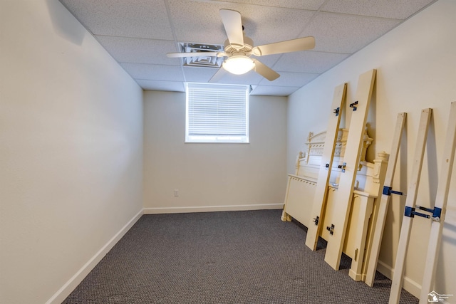 spare room featuring ceiling fan, a paneled ceiling, and dark carpet