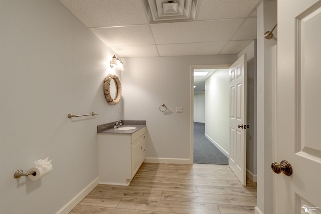 bathroom with vanity, hardwood / wood-style floors, and a drop ceiling