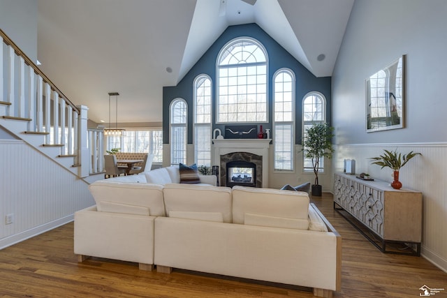 living room with a high end fireplace, wood-type flooring, and vaulted ceiling