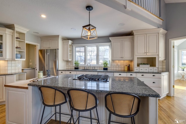 kitchen with sink, hanging light fixtures, light hardwood / wood-style flooring, appliances with stainless steel finishes, and a kitchen island