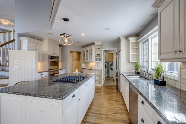 kitchen featuring appliances with stainless steel finishes, sink, hanging light fixtures, a center island, and washing machine and clothes dryer