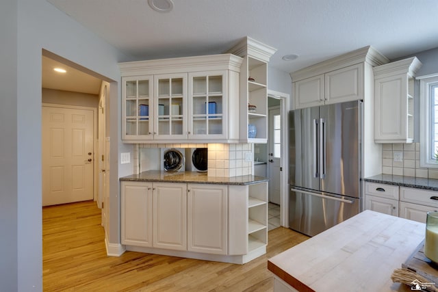 kitchen featuring white cabinetry, backsplash, stainless steel refrigerator, and light hardwood / wood-style flooring