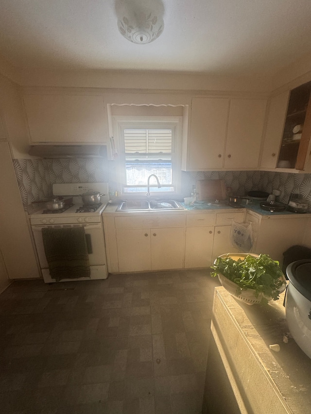 kitchen featuring tasteful backsplash, sink, white range with gas stovetop, and white cabinets