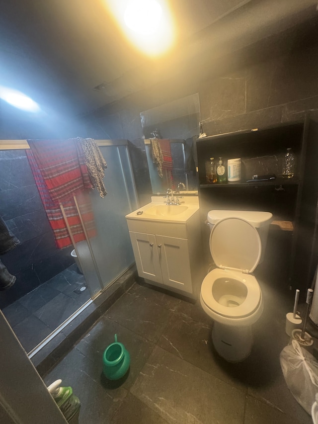 bathroom featuring vanity, toilet, and a shower with door