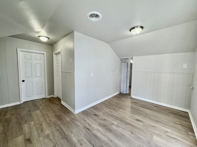 additional living space with vaulted ceiling and light hardwood / wood-style floors