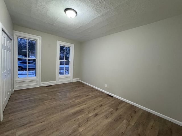 spare room featuring dark wood-type flooring and a textured ceiling