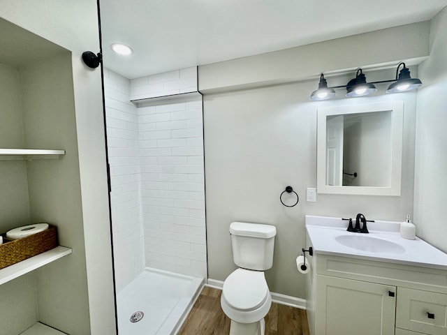 bathroom featuring vanity, hardwood / wood-style flooring, toilet, and a tile shower