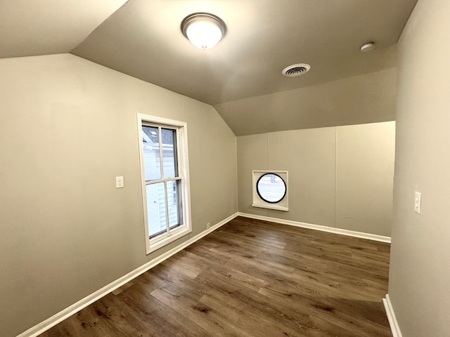 additional living space featuring vaulted ceiling and dark wood-type flooring