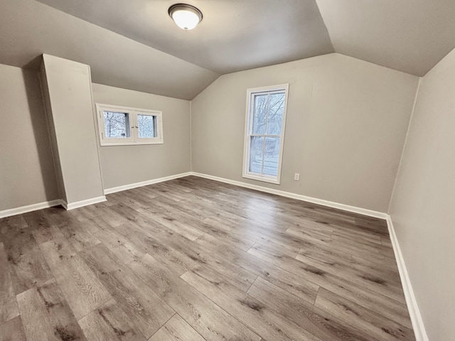 bonus room featuring hardwood / wood-style flooring, vaulted ceiling, and a healthy amount of sunlight