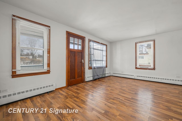 foyer featuring a baseboard heating unit, a wealth of natural light, and hardwood / wood-style floors