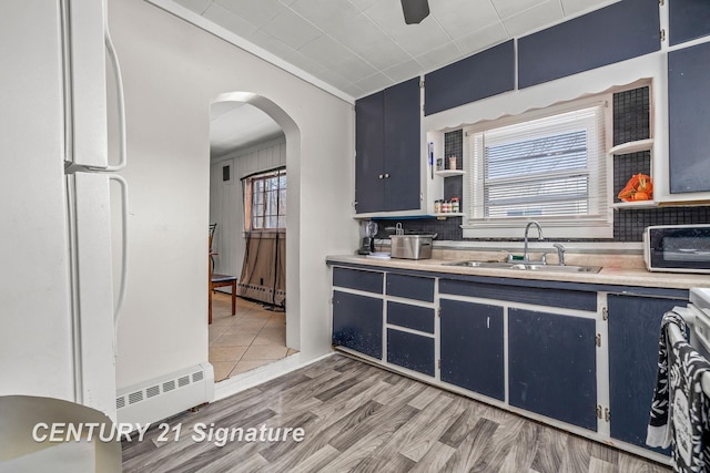 kitchen with blue cabinets, a baseboard heating unit, sink, and light wood-type flooring