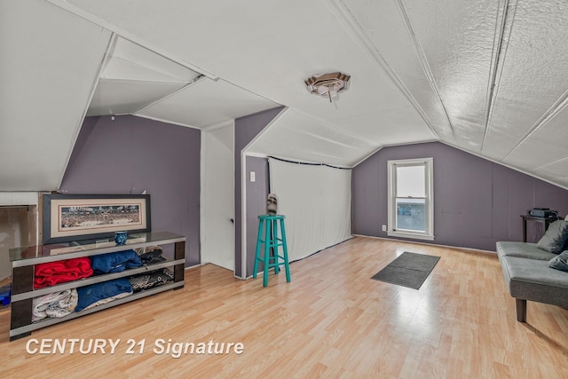 additional living space featuring wood-type flooring, vaulted ceiling, and a textured ceiling