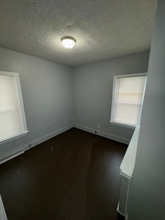 empty room featuring dark wood-type flooring and a textured ceiling