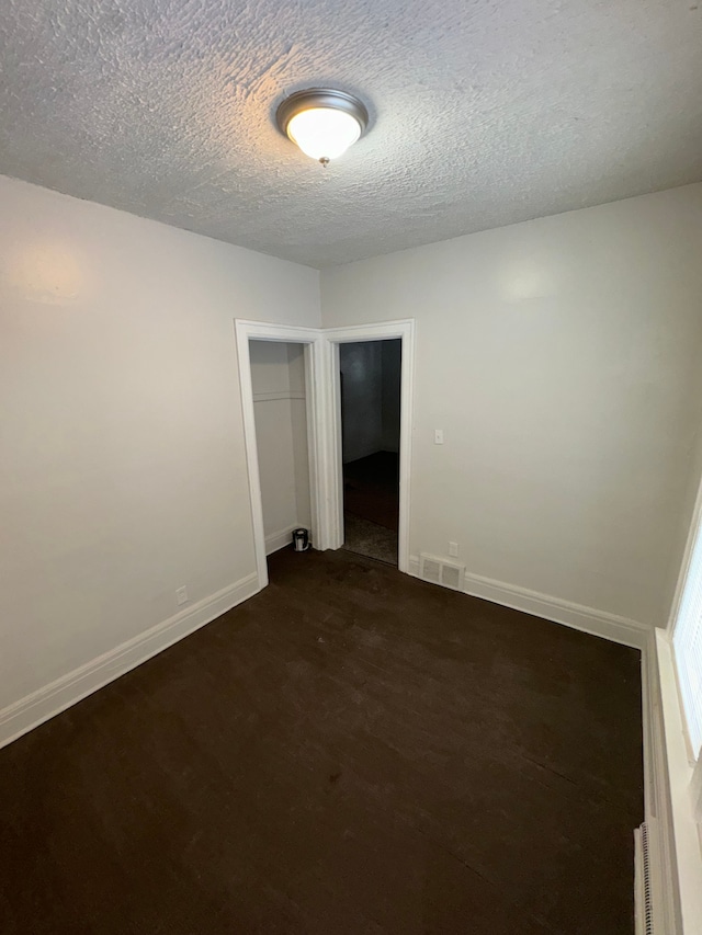 spare room with dark wood-type flooring and a textured ceiling