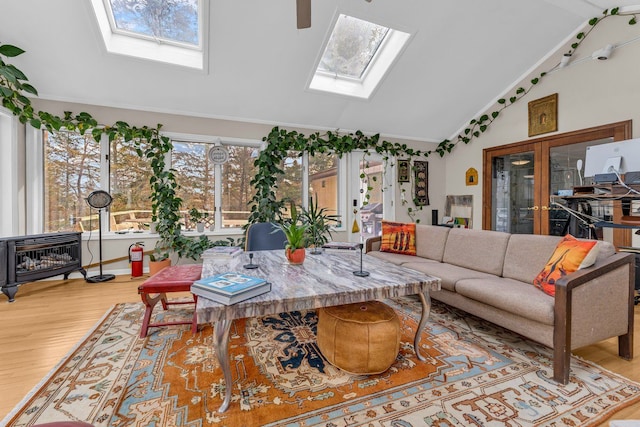 living room featuring light hardwood / wood-style flooring, ornamental molding, french doors, and vaulted ceiling with skylight