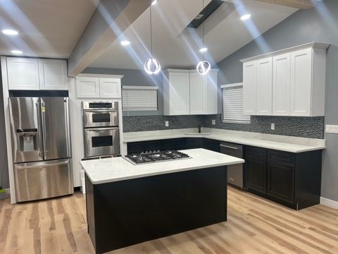 kitchen featuring sink, appliances with stainless steel finishes, hanging light fixtures, white cabinets, and a kitchen island