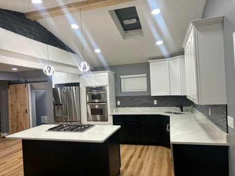 kitchen with hanging light fixtures, stainless steel appliances, a center island, white cabinets, and a barn door