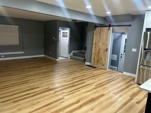 unfurnished living room with a barn door and light hardwood / wood-style floors