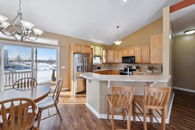 kitchen with appliances with stainless steel finishes, a breakfast bar, lofted ceiling, kitchen peninsula, and light brown cabinets