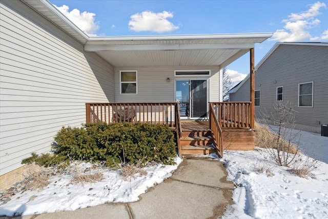 snow covered property entrance featuring central air condition unit