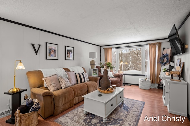 living room with hardwood / wood-style flooring, a baseboard radiator, ornamental molding, and a textured ceiling