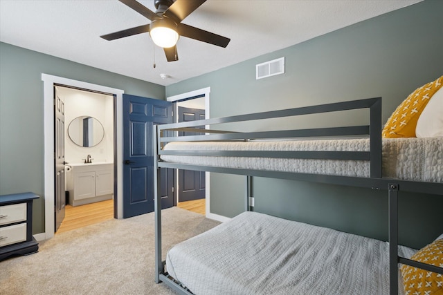 bedroom featuring light carpet, sink, ceiling fan, and ensuite bathroom