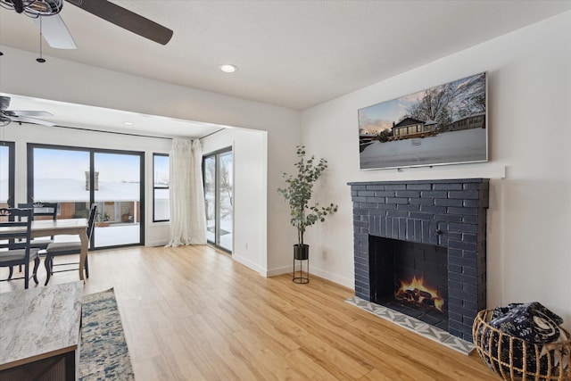 living room with a brick fireplace, hardwood / wood-style floors, and ceiling fan