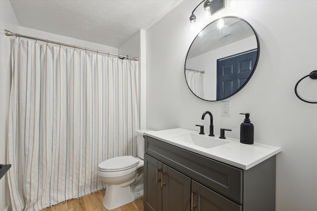 bathroom with wood-type flooring, toilet, a textured ceiling, and vanity