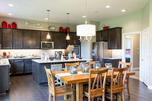 kitchen featuring pendant lighting, a center island, dark brown cabinetry, stainless steel appliances, and dark wood-type flooring