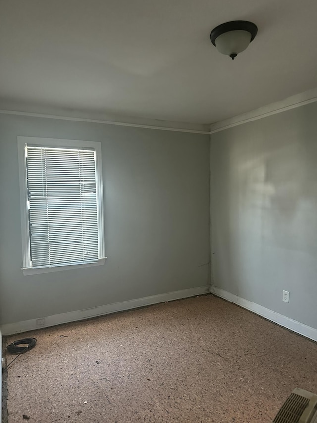 empty room featuring crown molding, baseboards, and speckled floor