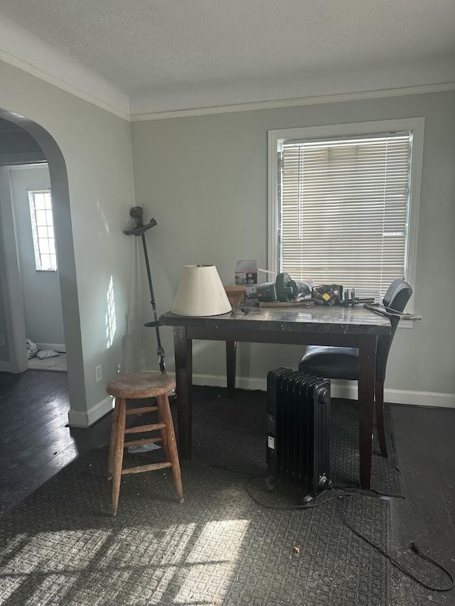 dining room featuring arched walkways, crown molding, radiator heating unit, a textured ceiling, and baseboards