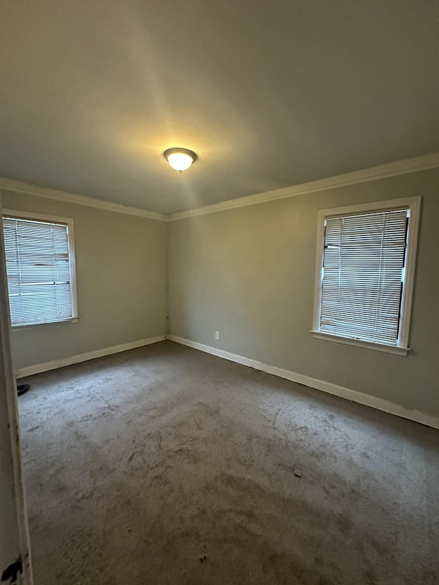 spare room with ornamental molding, dark carpet, and baseboards