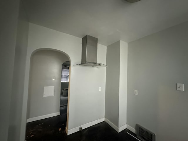 interior details featuring arched walkways, concrete floors, visible vents, baseboards, and wall chimney exhaust hood