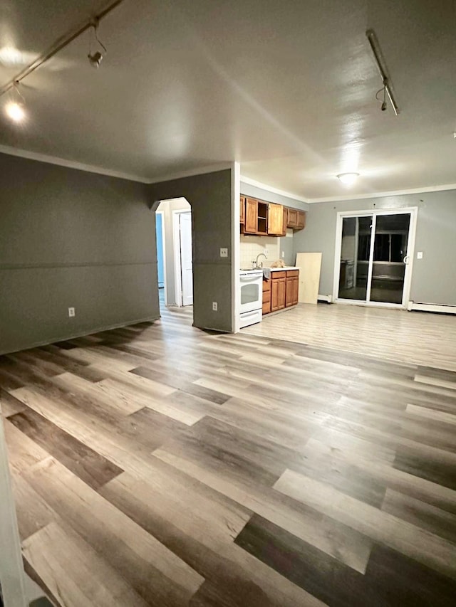 unfurnished living room with track lighting, ornamental molding, light hardwood / wood-style floors, and a baseboard heating unit