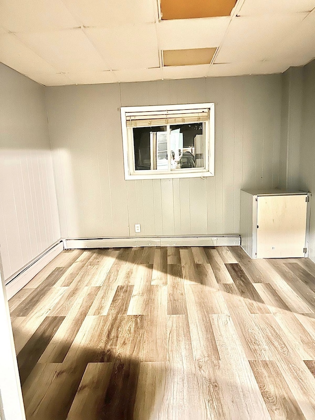 spare room with a baseboard radiator, wooden walls, and hardwood / wood-style floors