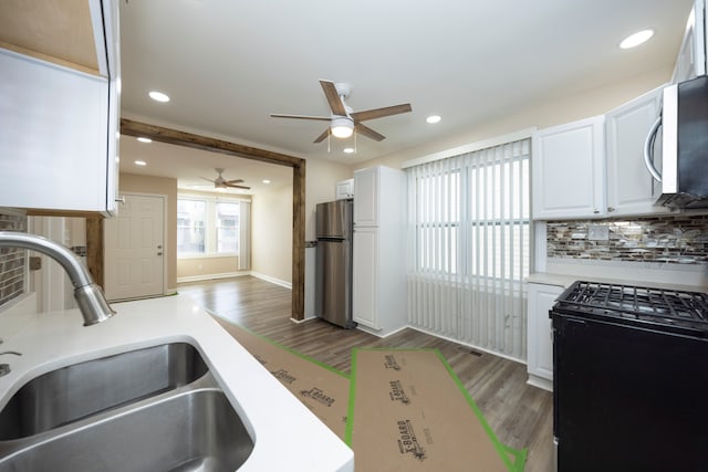 kitchen featuring sink, appliances with stainless steel finishes, white cabinetry, backsplash, and dark hardwood / wood-style floors