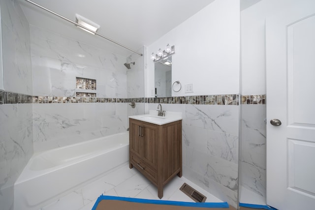 bathroom with vanity, tiled shower / bath, and tile walls