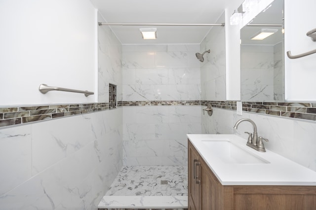 bathroom with vanity, tiled shower, and tile walls