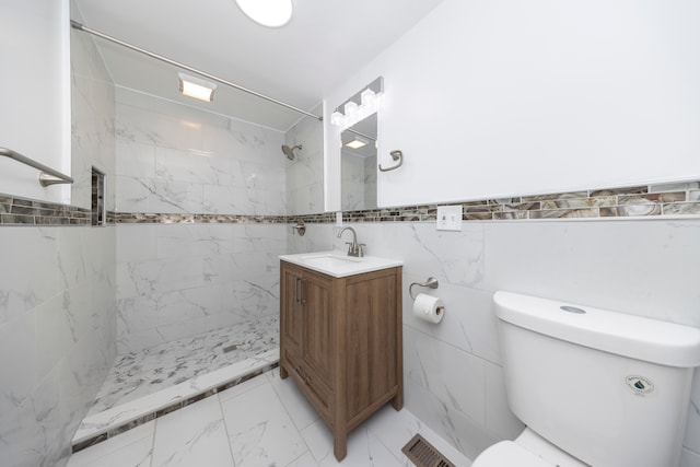 bathroom with vanity, tile walls, toilet, and tiled shower