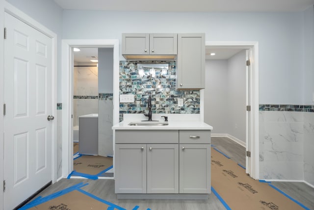 kitchen with backsplash, sink, light hardwood / wood-style floors, and gray cabinetry