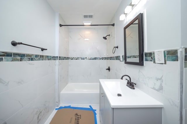 bathroom featuring vanity, tiled shower / bath combo, and tile walls