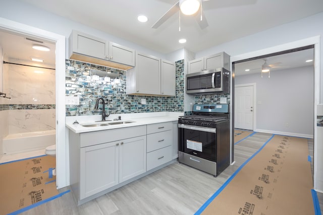 kitchen featuring stainless steel appliances, sink, light hardwood / wood-style flooring, and decorative backsplash