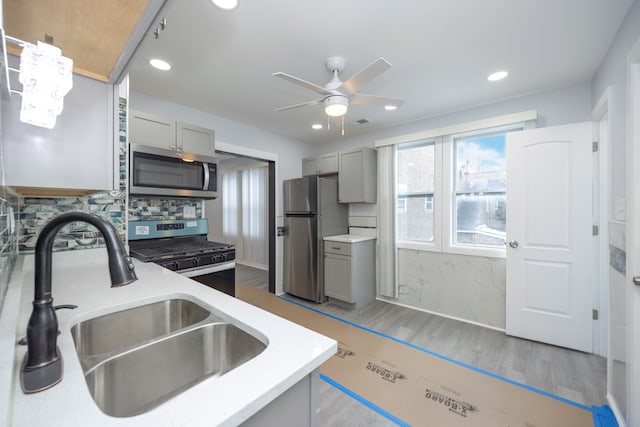 kitchen featuring gray cabinets, appliances with stainless steel finishes, sink, ceiling fan, and light hardwood / wood-style flooring