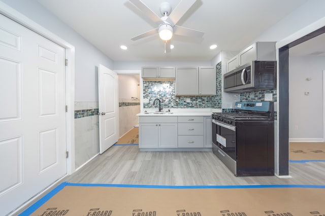 kitchen with sink, gray cabinets, ceiling fan, appliances with stainless steel finishes, and light hardwood / wood-style floors