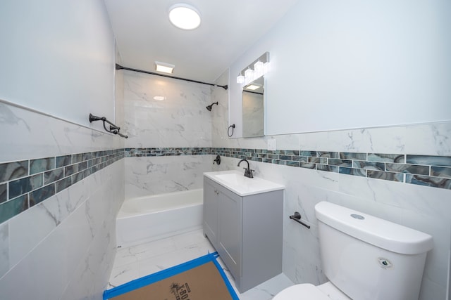 full bathroom featuring tiled shower / bath, vanity, toilet, and tile walls