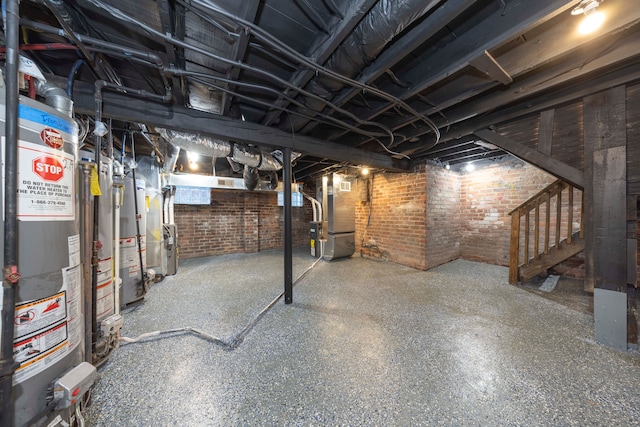 basement featuring brick wall, heating unit, and gas water heater