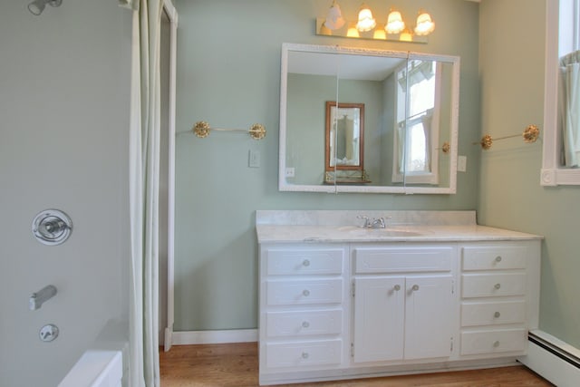 bathroom featuring vanity, shower / washtub combination, hardwood / wood-style floors, and a baseboard heating unit