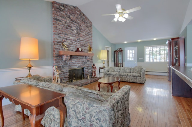 living room with light hardwood / wood-style flooring, ceiling fan, baseboard heating, high vaulted ceiling, and a fireplace